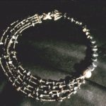Ras de cou assymétrique avec un côté du 1/3 du collier enfilé de grosses perles d'hématites cubiformes, terminé par une grosse perles argent avec motifs puis plusieurs rangs de rocaille anthracite et petites hématites sur les 2/3 restants