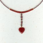 Collier ras de cou et son pendant central finissant avec un coeur en cornaline rouge, le tout enfilé avec des petites perles rondes de grenats et petites cornalines tubes