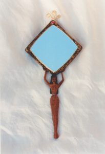 Miroir à main en acajou sculpté et teint, représentant une femme nue cheveux longs et noir portant le miroir sur sa tête