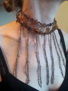 Tour de cou en plastron avec enfilage de perles de rocaille, perles de bois, ambre et pierres fines mauves et ses pendants longs et fins de perles de rocailles et petites ayolites mauves