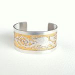 Création bracelet manchette pièce unique en laiton avec motif de dragon argenté en relief tout autour, et le fond ciselé et doré