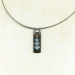 Création Pendentif ébène rectangle avec 3 labradorites blanches ovales enfilées sur fil d'or puis riveté sur l'ébène avec b^lière en argent
