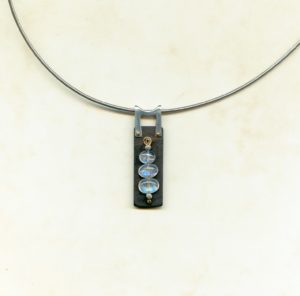 Création Pendentif ébène rectangle avec 3 labradorites blanches ovales enfilées sur fil d'or puis riveté sur l'ébène avec b^lière en argent