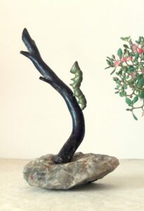 Sculpture 15 cm petite chenille bronze patiné vert grimpant sur branche de corail noir soclée sur un caillou de ballade