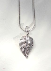 Pendentif création pièce unique d'une feuille en argent toute gravée de nervures et son pétiole accroché sur la chaîne