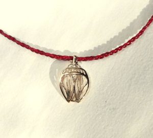 Pendentif Scarabée stylisé ajouré et ciselé en or monté sur une tresse fine de fleur de cuir rouge