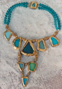 Collier plastron avec tessons de verre couleur bleus et verts cerclés de résine dorée et montés avec perles de bois et verre