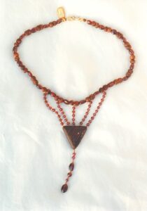 Collier ras de cou petit plastron perles en bois et grenats avec son pendentif triangle pointe en bas en bois de wenge, clou doré apparaissant, et breloque de gouttes de grenats finissant