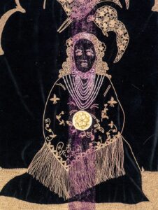 Médaillon ciselé Fleur de Vie parant le cœur de l'enfant sur la tapisserie brodée Adama