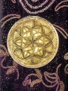 Médaillon ciselé Fleur de Vie accroché sur la tapisserie brodée Adama