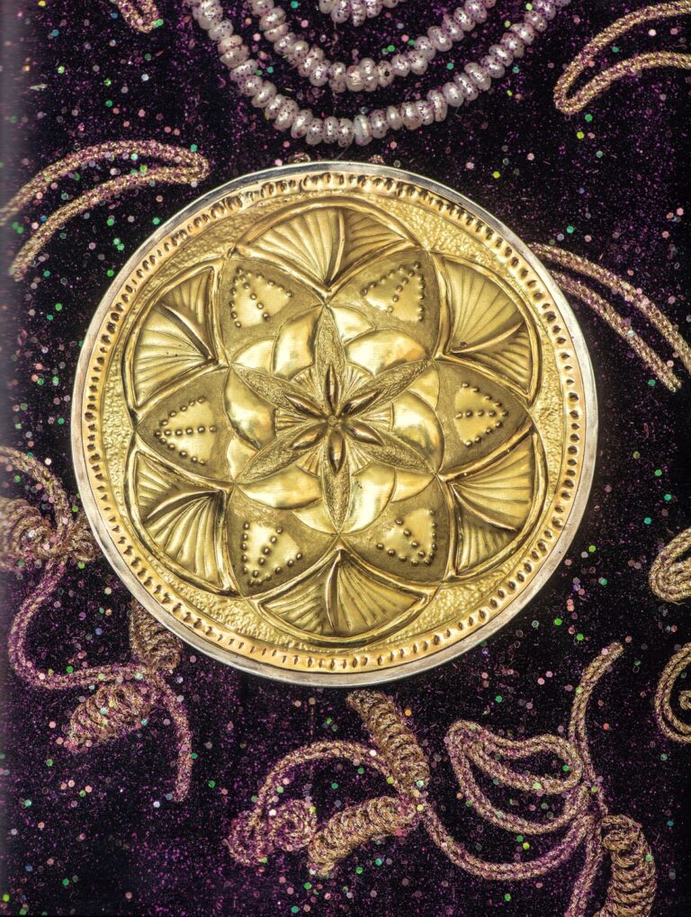 Médaillon ciselé Fleur de Vie accroché sur la tapisserie brodée Adama